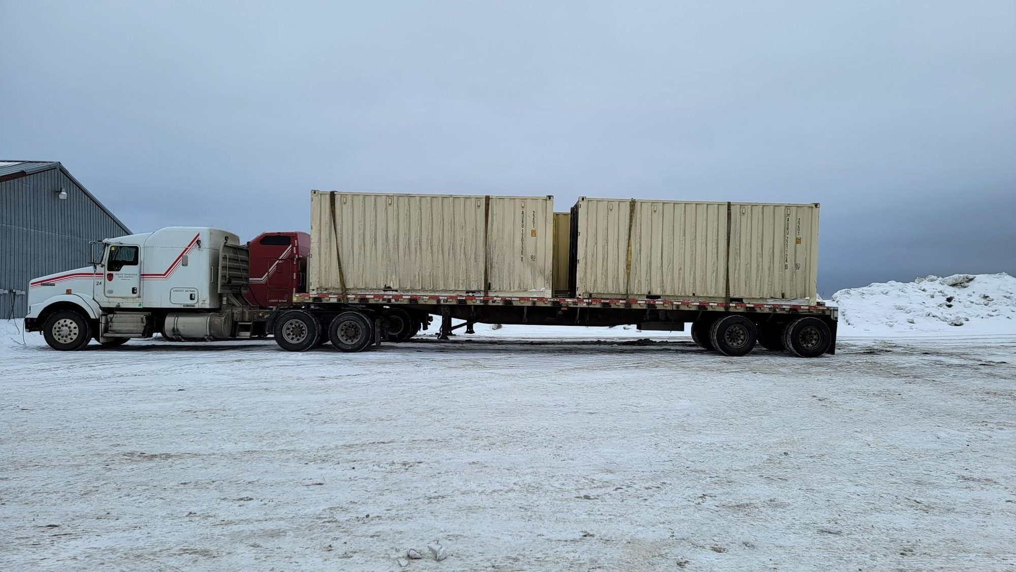 Flatbed hauling shipping containers through winter conditions